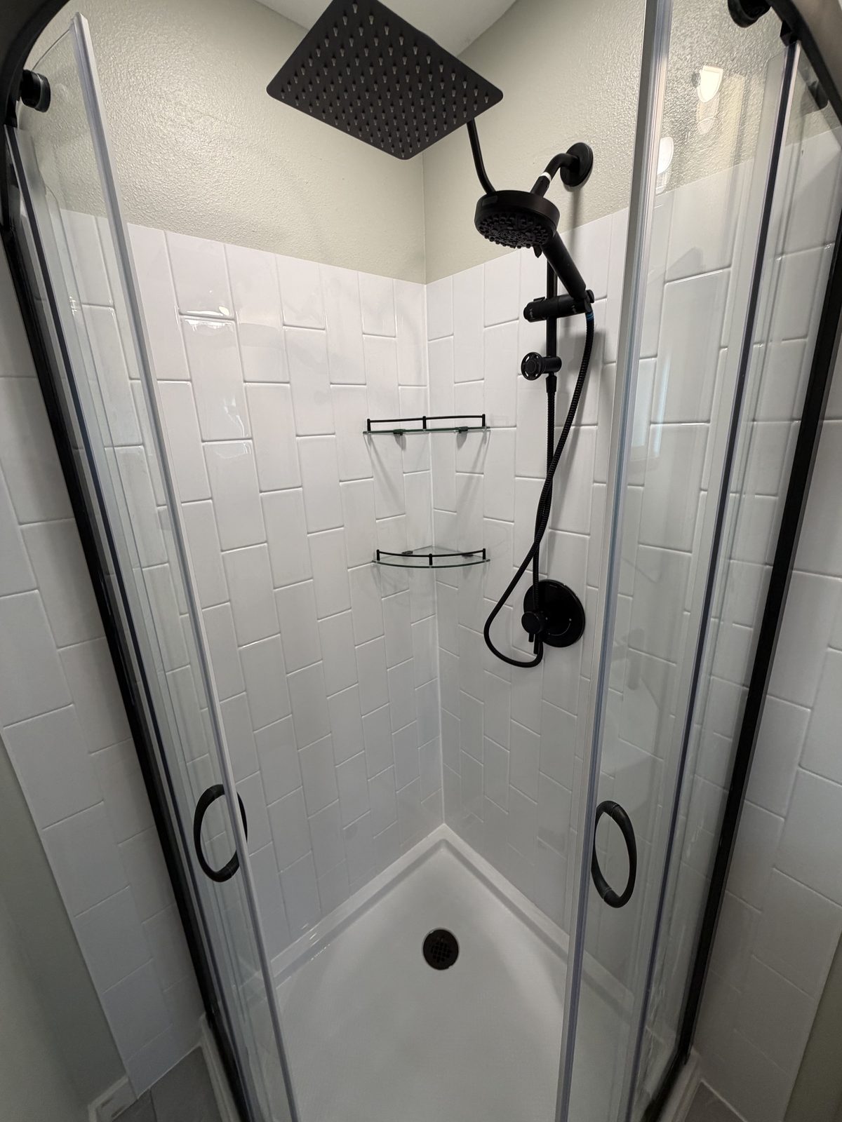 Neo-angle pan, acrylic simulated tile, glass door. Bathroom remodel in Puyallup by DA Interior Solutions
