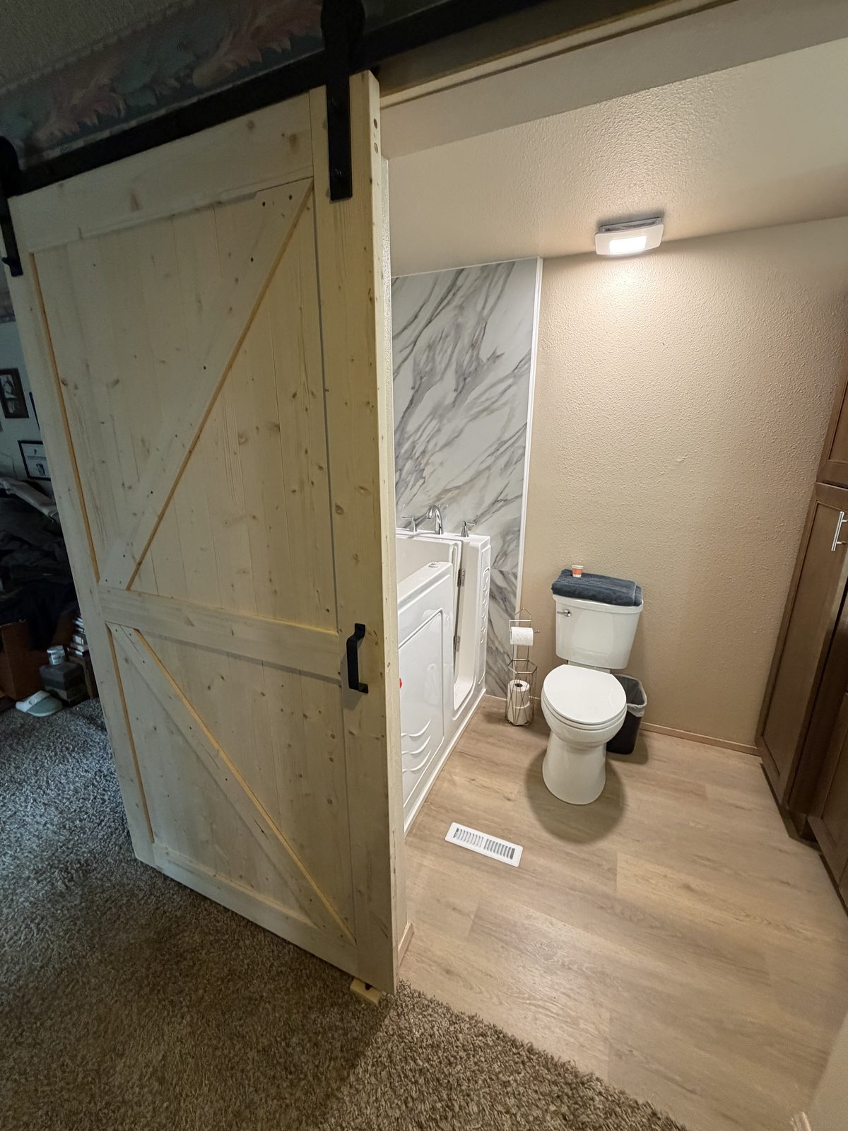 A sliding door into the bath, quartz walls beyond. Kitchen and bathroom in Puyallup by DA Interior Solutions